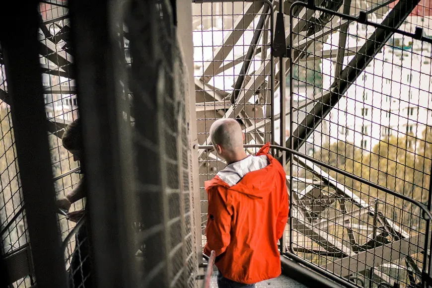 Man in red jacket walking down the stairs of eiffel tower